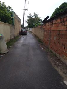 an empty street with a brick wall and a car at Vila Bárbara térreo in Araruama