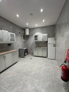 a large kitchen with white appliances and tile floors at الملاذ الهادي in Al-ʿUla