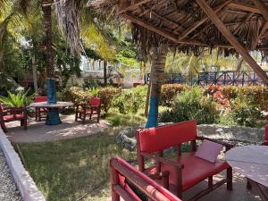 a group of tables and chairs under a straw umbrella at Karafuu Nyama Choma Lodge in Bwejuu