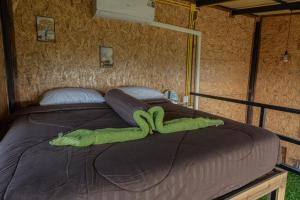 a green stuffed animal laying on a bed at Sunray Hill in Ranong