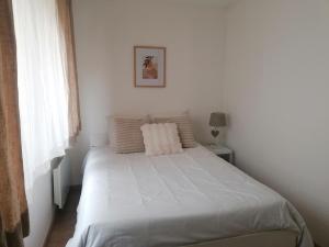 a white bed in a white bedroom with a window at Chambre double avec salle de bain commune, a 2 min de la Croisette in Cannes