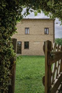 a brick house behind a wooden fence with a gate at Tenuta Gran Bosco in Loro Piceno