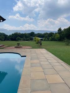 a stone walkway next to a swimming pool with a statue at Hartbeespoort Escape Hot Tub and Mountain Views in Skeerpoort