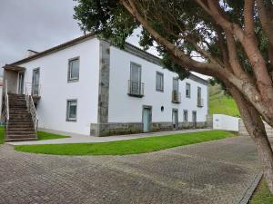 a white building with a tree in front of it at Retiro das Camélias 3 in Lajes das Flores