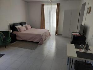 a bedroom with a bed with pink pillows and a television at Retiro das Camélias 3 in Lajes das Flores