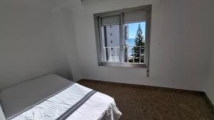 a white room with a bed and a window at Frontal con vistas in Benicàssim