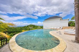 a swimming pool with chairs and a house at Kelingking Parama Resort in Nusa Penida