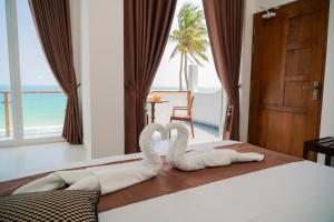 two swans made to look like hearts sitting on a bed at Trinco Beachfront Villas AJS in Trincomalee