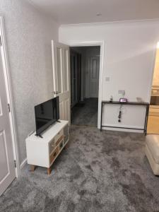 a living room with a flat screen tv on a white cabinet at Plum Cottage in Keswick