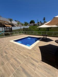 a swimming pool with a table and an umbrella at Casa 2 quarto em condomínio in Camaçari