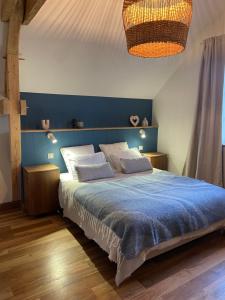 a bedroom with a blue bed with two pillows at La Villa de Paul - Les Chambres in Yenne