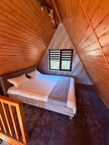 a large bed in a wooden room with a window at Cabana AFrame Olanesti in Băile Olăneşti