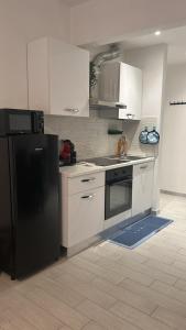 a kitchen with white cabinets and a black refrigerator at Casa Conchiglia 6 ospiti 5 minuti a piedi da mare, centro e stazione comfort completo in Rapallo