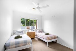 a bedroom with two beds and a window at Mooloolaba Parkway Palms Spacious 3BR with Patio & BBQ Pet-Friendly near the Beach in Mooloolaba