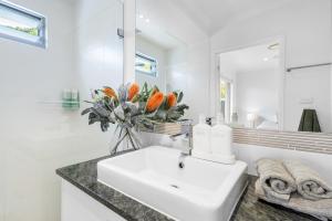 a white bathroom with a sink and a mirror at Mooloolaba Parkway Palms Spacious 3BR with Patio & BBQ Pet-Friendly near the Beach in Mooloolaba +21 photos