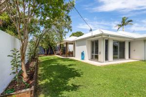 a house with a green lawn in front of it at Mooloolaba Parkway Palms Spacious 3BR with Patio & BBQ Pet-Friendly near the Beach in Mooloolaba