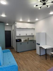 a living room with a blue couch and a kitchen at NBG Aparthotel in Batumi