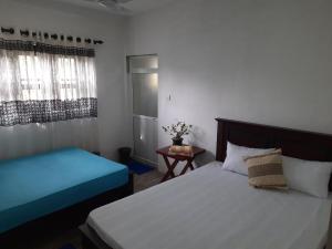 a bedroom with two beds and a table and a window at AIRA in Galle