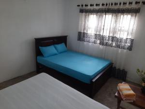 a bedroom with a bed with blue sheets and windows at AIRA in Galle