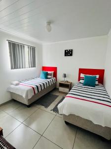 two beds in a room with red and white at Covenant Place in Cape Town