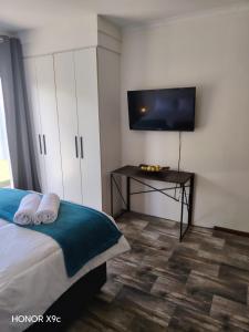 a bedroom with a bed and a tv and a table at Urban Nest Self Catering in George +3 photos