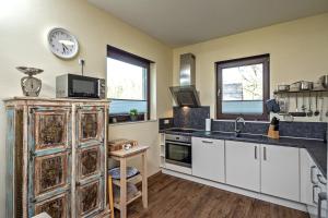 a kitchen with white cabinets and a clock on the wall at Ben in Lenz +13 photos