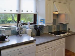 a kitchen with white cabinets and a sink and a window at Rosecraddoc Manor - Riverview in Saint Cleer
