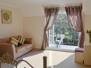a living room with a couch and a sliding glass door at Rosecraddoc Manor - Riverview in Saint Cleer
