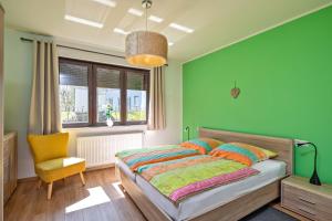 a green bedroom with a bed and a yellow chair at Lago EG in Lenz