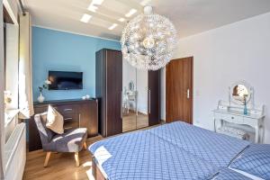 a bedroom with a blue bed and a chandelier at Lago EG in Lenz +5 photos