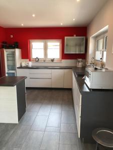a large kitchen with red walls and white cabinets at Michael in Lenz