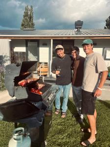 three men standing next to a barbecue grill at Penny's Drop Inn in Cromwell