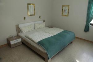 a bedroom with a bed with a blue blanket on it at Pension Schiffer in Blankenheim