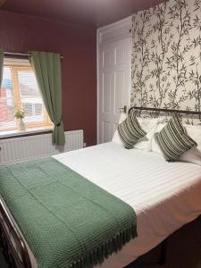 a bedroom with a bed with a green blanket and a window at The Black Swan Inn in Leominster