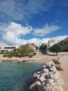 a beach with rocks in the water and buildings at Apartment Grey in Mandre