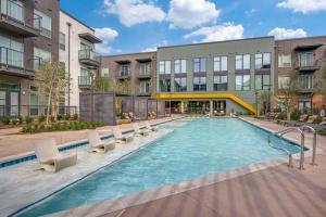 a swimming pool with chairs in front of a building at Landing Chic 3BD Clubhouse Pool in Denton