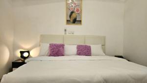a bedroom with a white bed with purple pillows at The Basileia Court in Janman