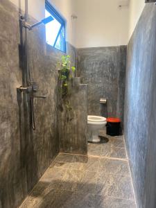 a bathroom with a toilet and a plant in the shower at Bamboo Garden Inn in Goiyapana