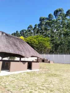 a grass roofed building with benches in a field at Roxy's in Richards Bay