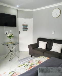 a living room with a couch and a clock on the wall at Roxy's in Richards Bay