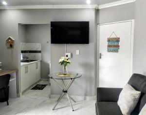 a living room with a table and a tv on the wall at Roxy's in Richards Bay