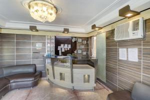 a lobby with a bar with leather chairs and a chandelier at Hotel O Mukut Mahal in Meerut +31 photos