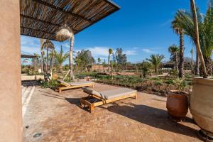 a patio with two beds and palm trees at VILLA 2s in Marrakesh