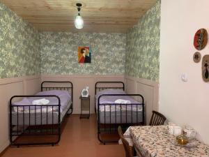 two beds in a room with a table and a table and chairs at Guesthouse Lantia in Mestia