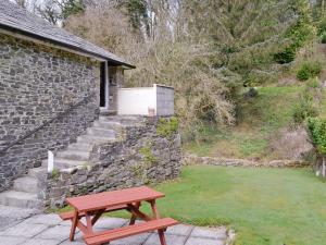 a wooden picnic table sitting next to a stone wall at Rosecraddoc Manor - Hayloft in Saint Cleer +7 photos