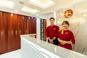 a man and a woman standing in front of a hotel at Bailey Hotel Hue in Hue