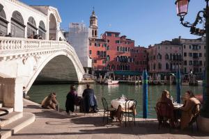 a group of people sitting at tables near a bridge at Ca' Della Loggia in Venice