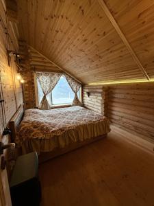 a bed in a wooden room with a window at Birtvisi Dream House in Abrameti