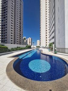 a large pool with blue water in front of tall buildings at Flat com 1 quarto e sala in Goiânia