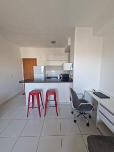 a kitchen with two red chairs and a counter at Flat com 1 quarto e sala in Goiânia